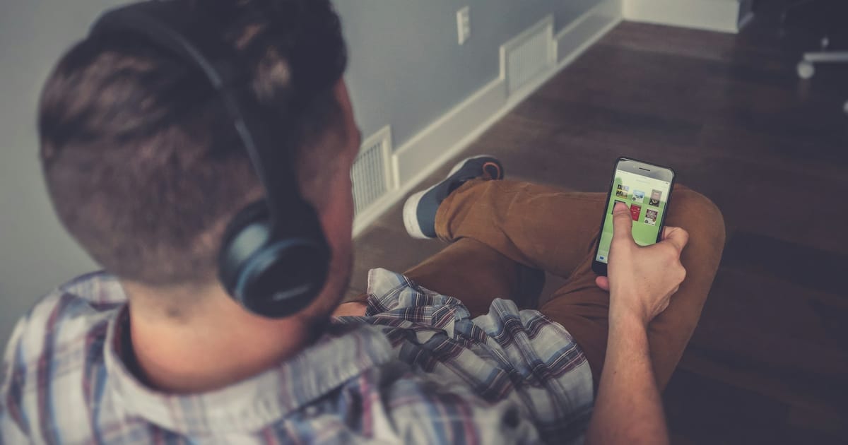 Una persona ve un video en su celular con audífonos puestos.