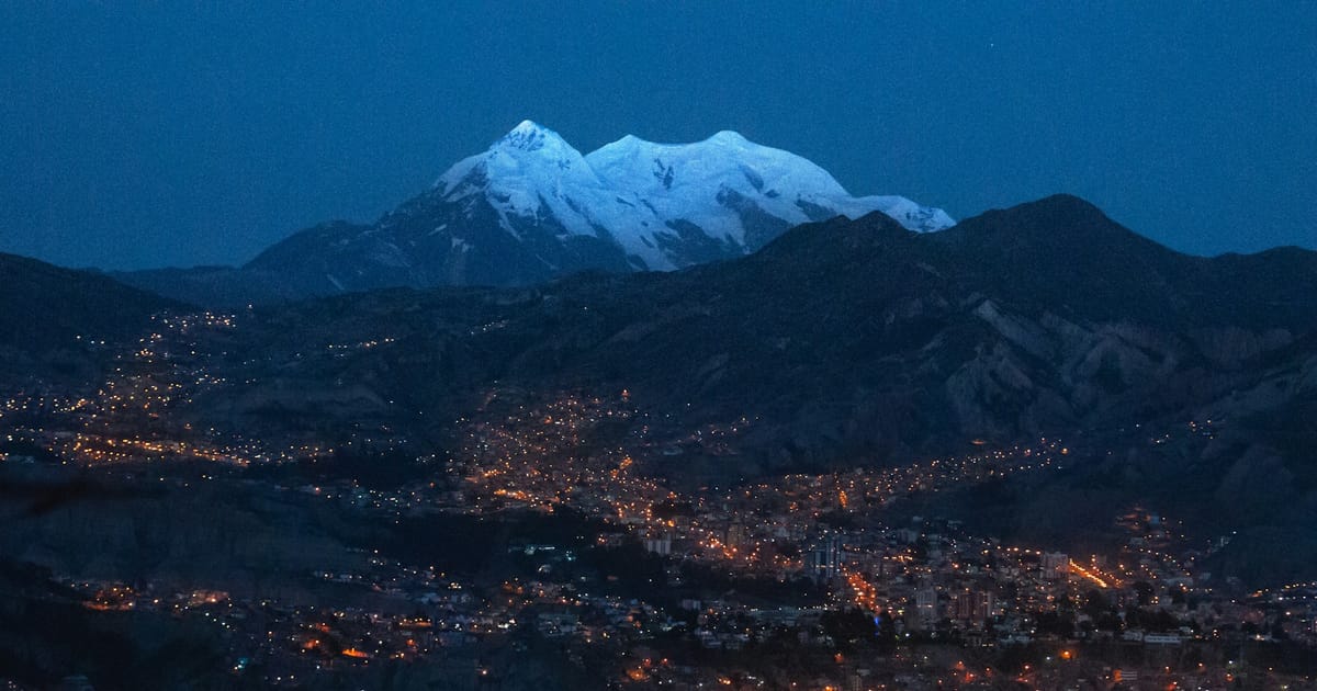 El Illimani nevado al anochecer, sobre las luces de la ciudad de La Paz.