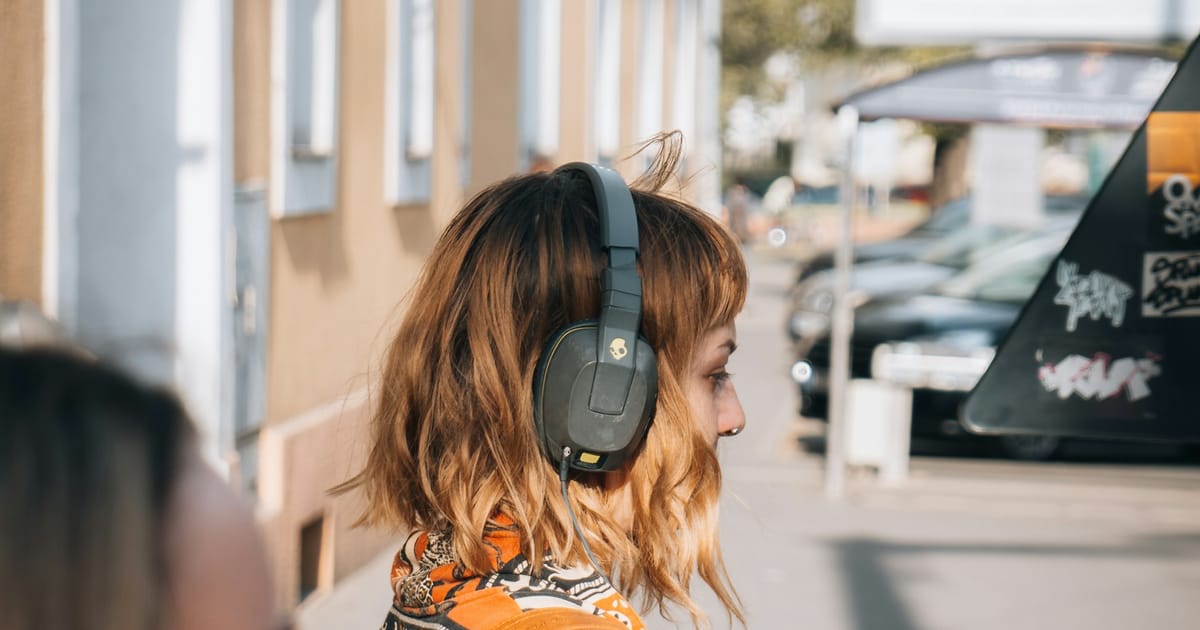 Una mujer con audífonos puestos, escuchando música.