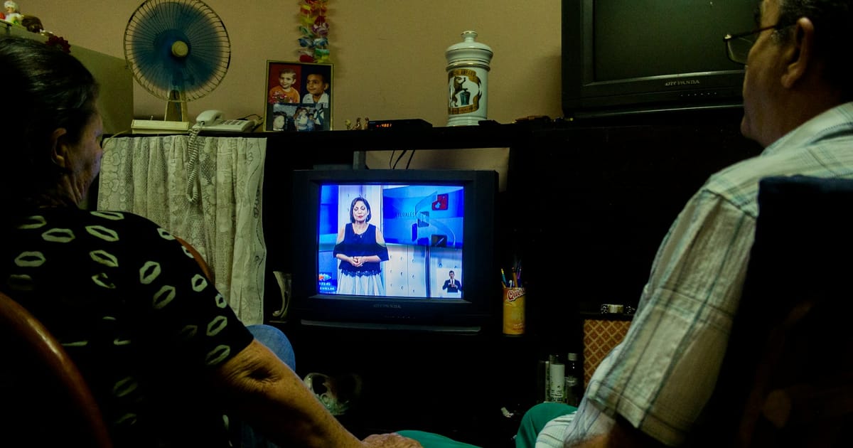 Una pareja mira la televisión en la sala de su casa.